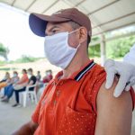 Homem recebe vacina durante atendimento em uma unidade de saúde ao ar livre.