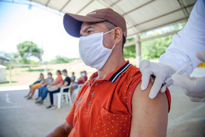Homem recebe vacina durante atendimento em uma unidade de saúde ao ar livre.