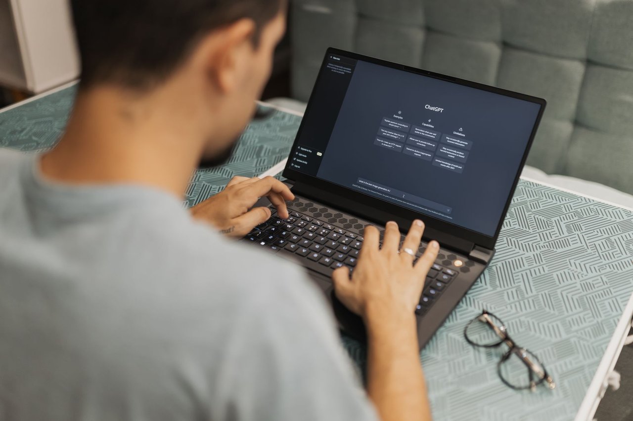 Pessoa utiliza um laptop com uma interface de inteligência artificial, concentrada em um ambiente interno.